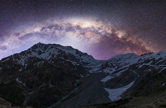 Snowy mountains with a starry night sky behind them