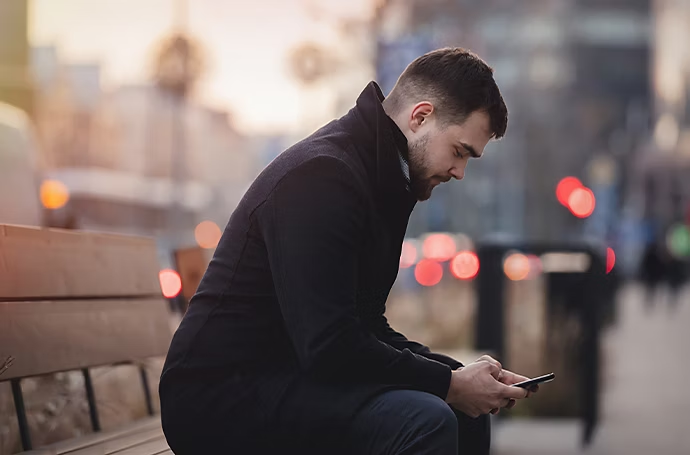 Ragazzo seduto su una panchina in città con sfondo bokeh