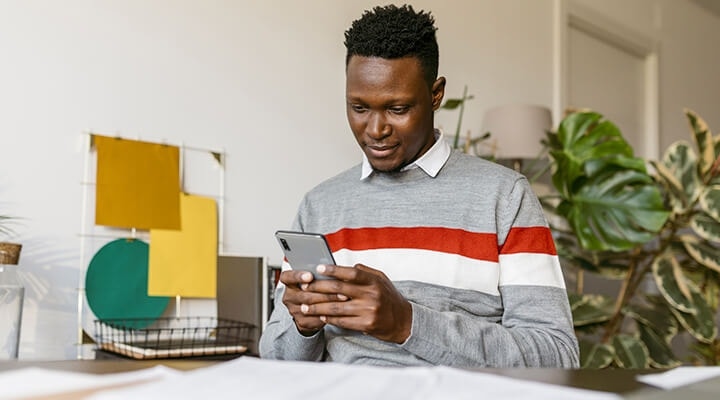 A young man sitting at their desk signing a PDF document on their iPhone