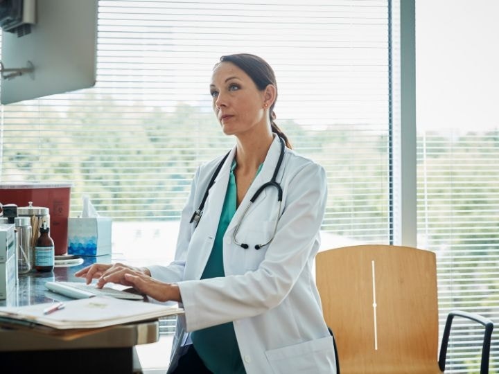 A doctor types out an informed consent form on the computer located in an exam room using Adobe Acrobat Sign