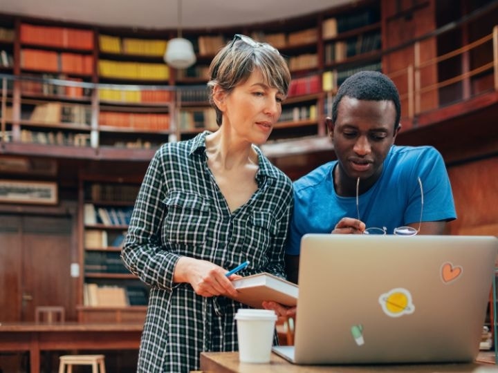 A professor and student looking over a letter of recommendation on a laptop before it is signed using Adobe Acrobat Sign