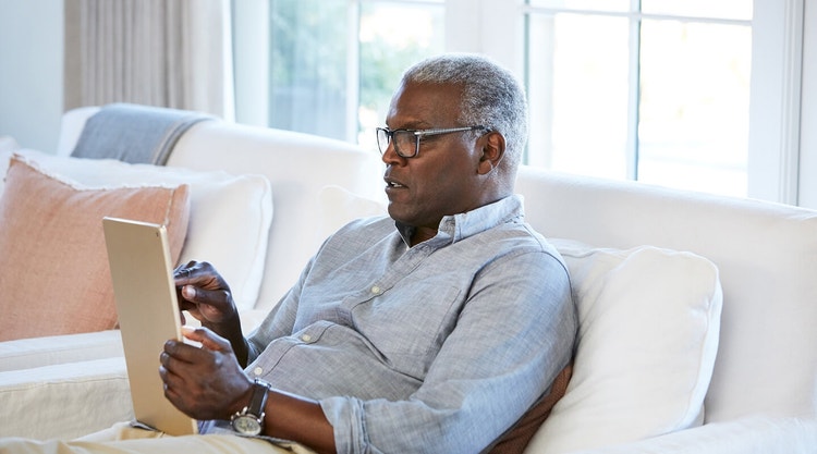 A person sitting on their couch signing a document using their iPad