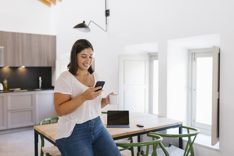 A person standing in their kitchen signing a PDF document on their iPhone