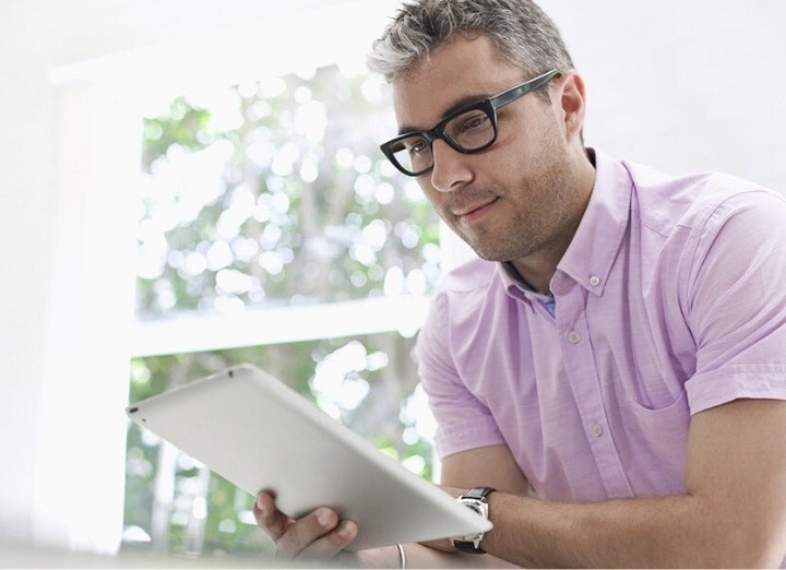 A photo of a person looking at something on a tablet they are holding in their hand.