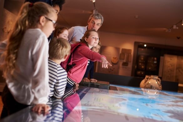 A student pointing something out to their class on an interactive map during a class trip