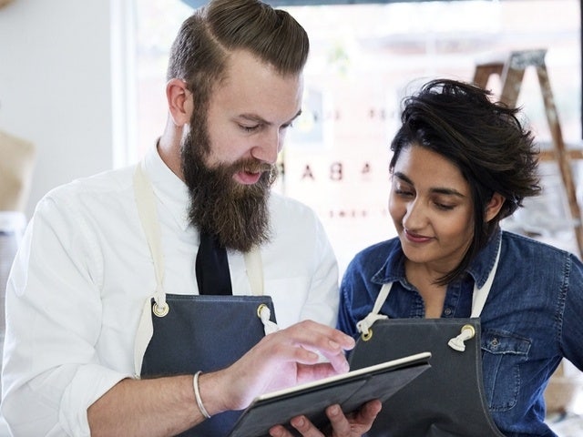 A photo of two business partners reviewing a paperless document together on a tablet device