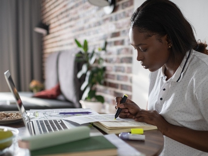 A college student working on homework at a table in their apartment