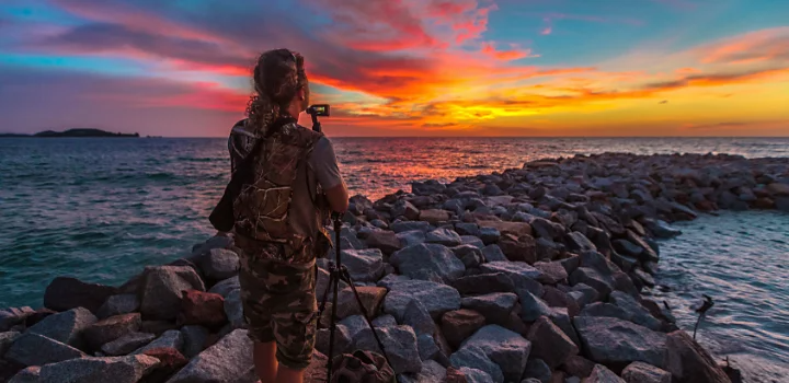 ビーチの入り江から夕日の写真を撮る写真家