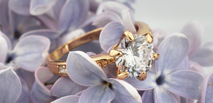 Macro photo of a diamond ring resting on a bed of lavender flowers