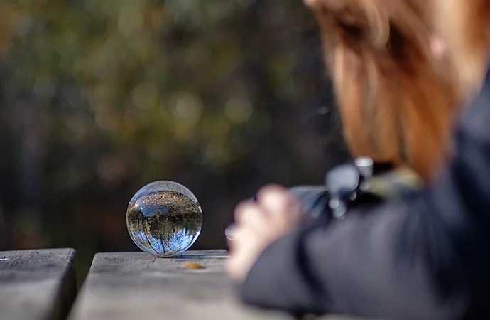 A person taking a photo of a lensball that is on top of a table