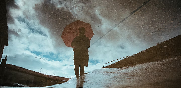 A photo of a person holding an umbrella on a rainy day.