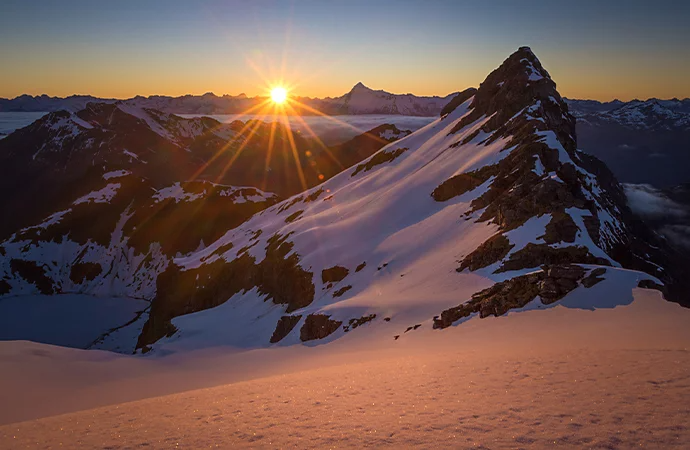 A sunrise illuminating a snow-covered mountain