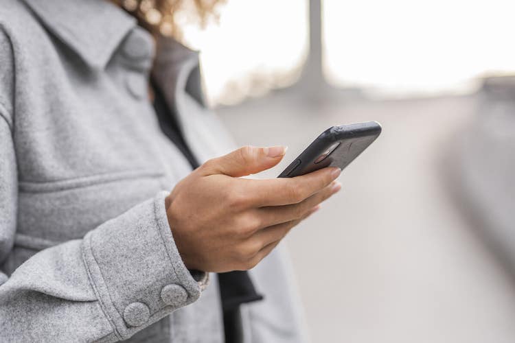 A person holding a mobile phone in their hand while providing an s-signature on a digital document