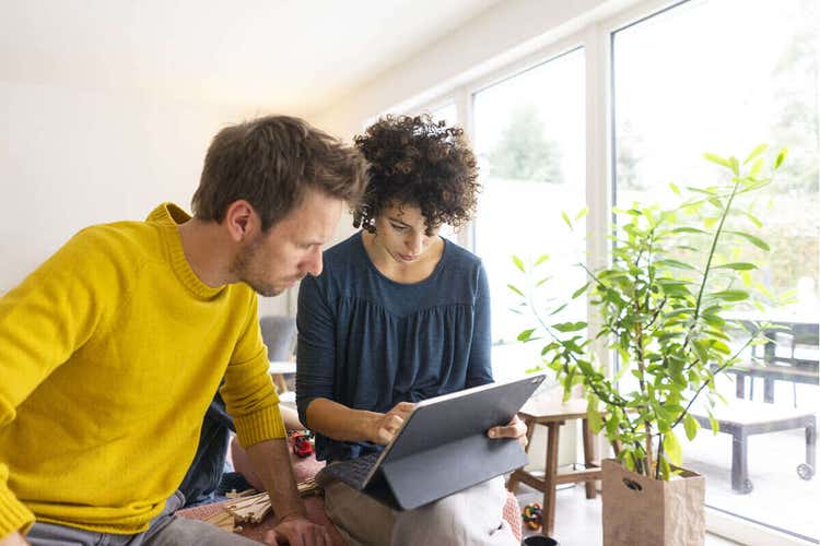 Two potential tenants standing and looking down at a house rental agreement on a tablet device