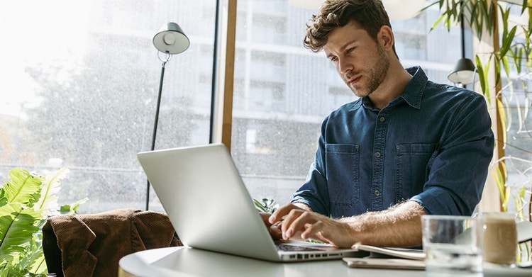 A person working on their laptop in a sunlit office