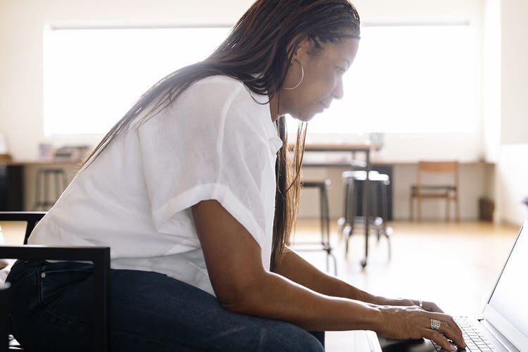 A business owner creating an invoice on their laptop at a coffee table