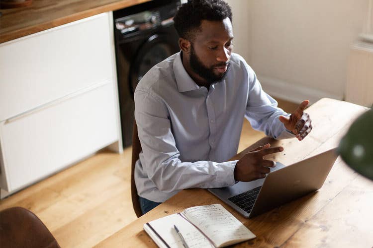 A business person working at a wooden table on their laptop