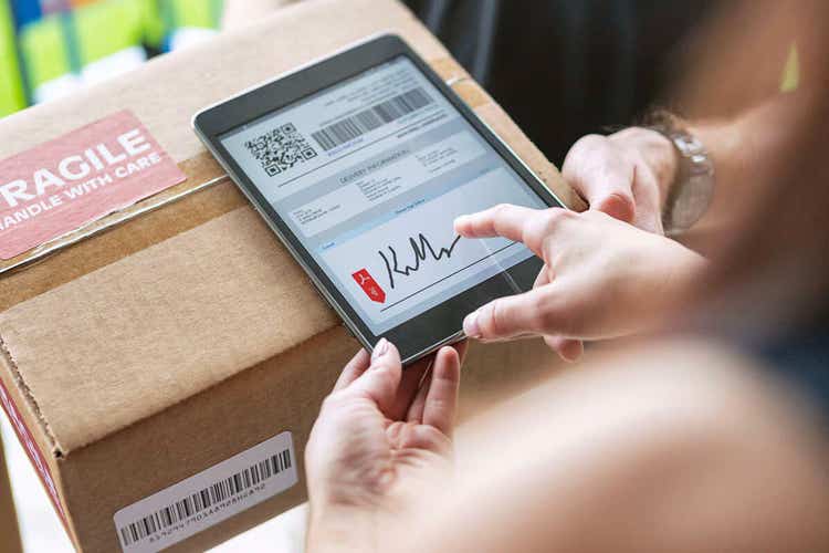 A close up of a woman's hands signing a bill of lading form for a package on a tablet.