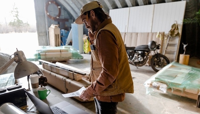 A business owner looking over shipping documents in their warehouse surrounded by newly acquired supplies