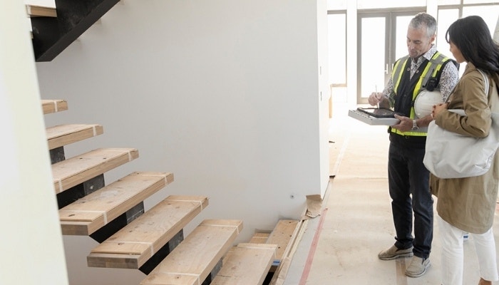 A subcontractor signing a bid with Acrobat Sign in a job site stairwell while their client looks on