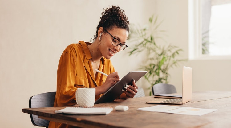 A homeowner sitting at a table filling out information for a real estate contract on their tablet device