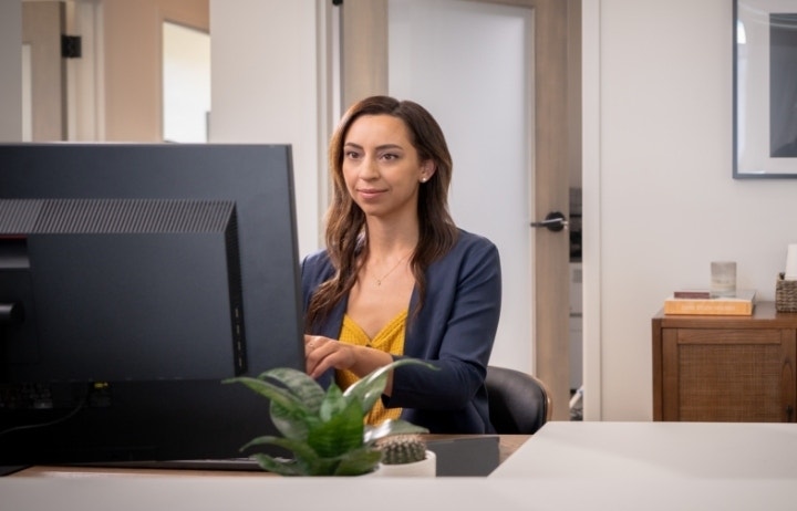 An image of a person sitting at a desk in an office using a computer.