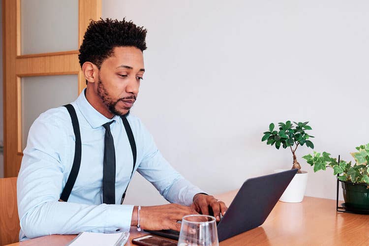 A person sitting at their desk writing a letter of intent to purchase on their laptop