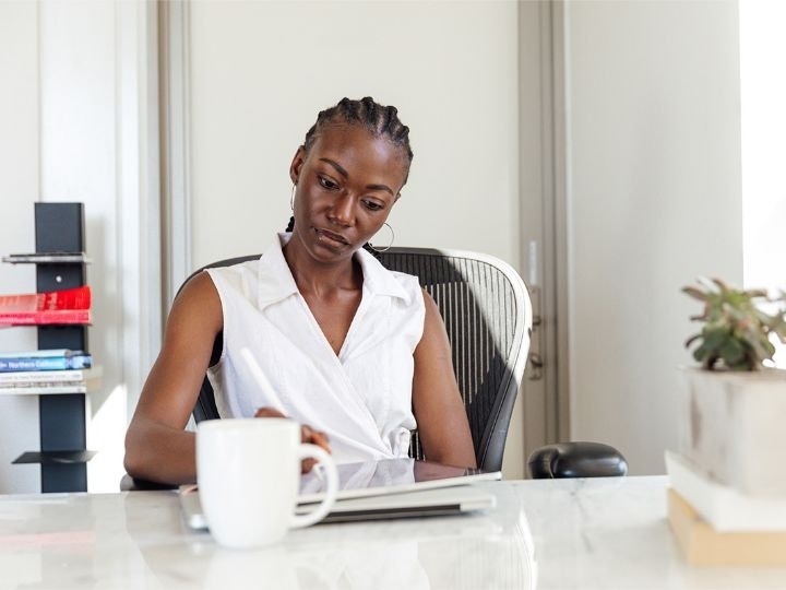 An image of a person sitting at a desk in an office using a tablet with a stylus in their hand.