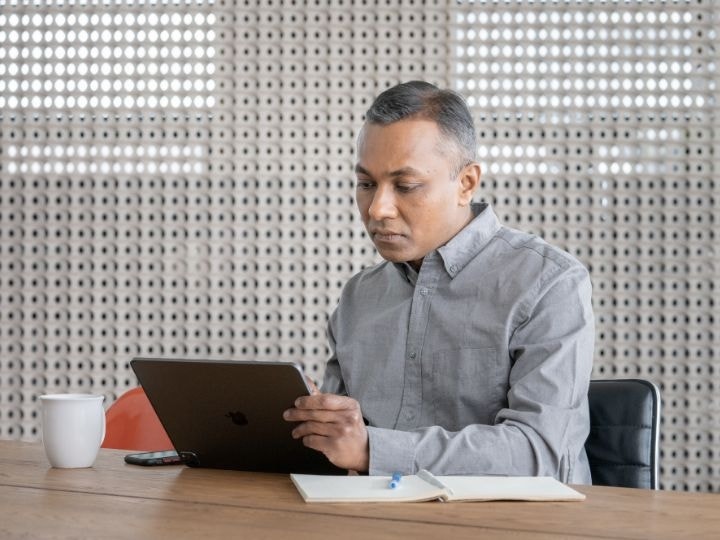 A photo of a person sitting at a table in a conference room and working on a laptop computer.