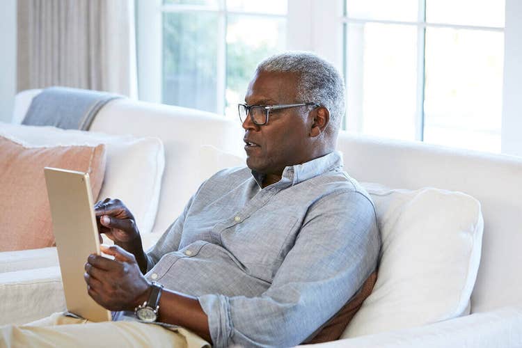 A person sitting on their couch signing a document using their iPad