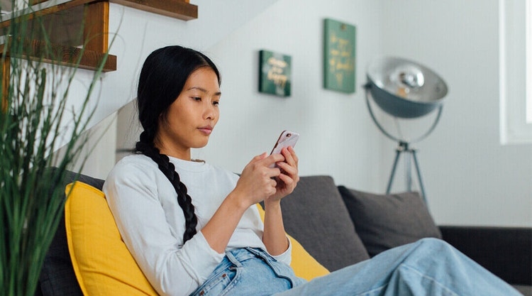 A business owner sitting on a couch reviewing a confidentiality agreement via their mobile phone