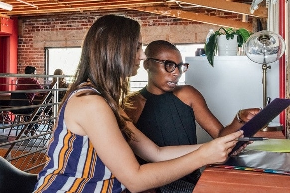 A person showing their concerned-looking coworker an agreement document.