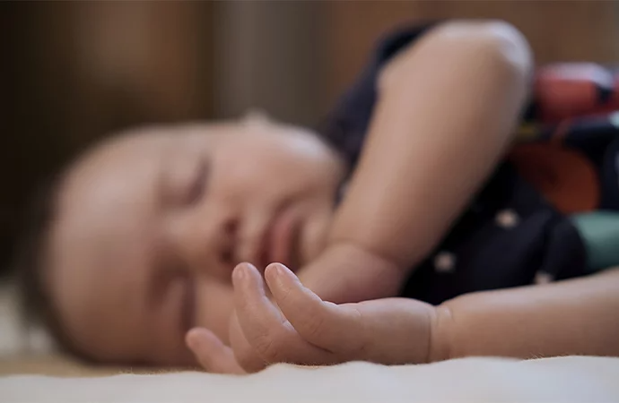 A photo of a baby sleeping on the floor with their face out of focus