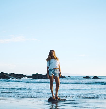 Leveraging the rule of thirds to photograph a woman standing on a rock in the ocean