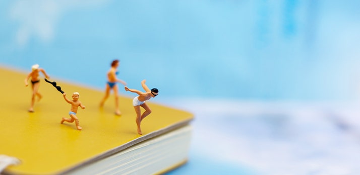 Tiny figurines, photographed in macro, playfully posed on a book