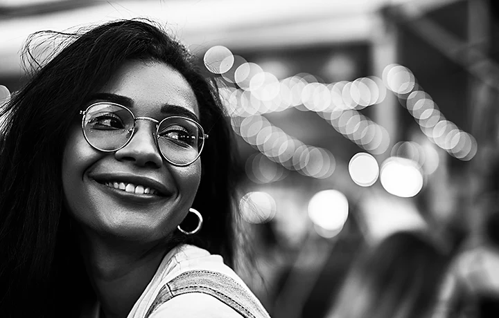 A black-and-white image of a smiling person looking back over their shoulder