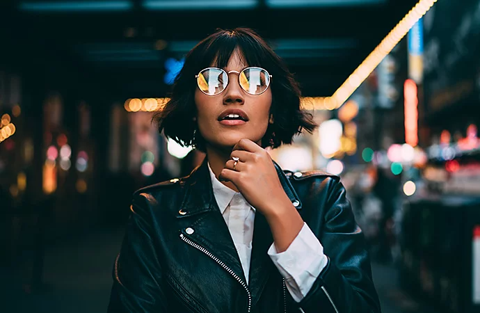 A color photograph of a person in a leather jacket reading something in the distance