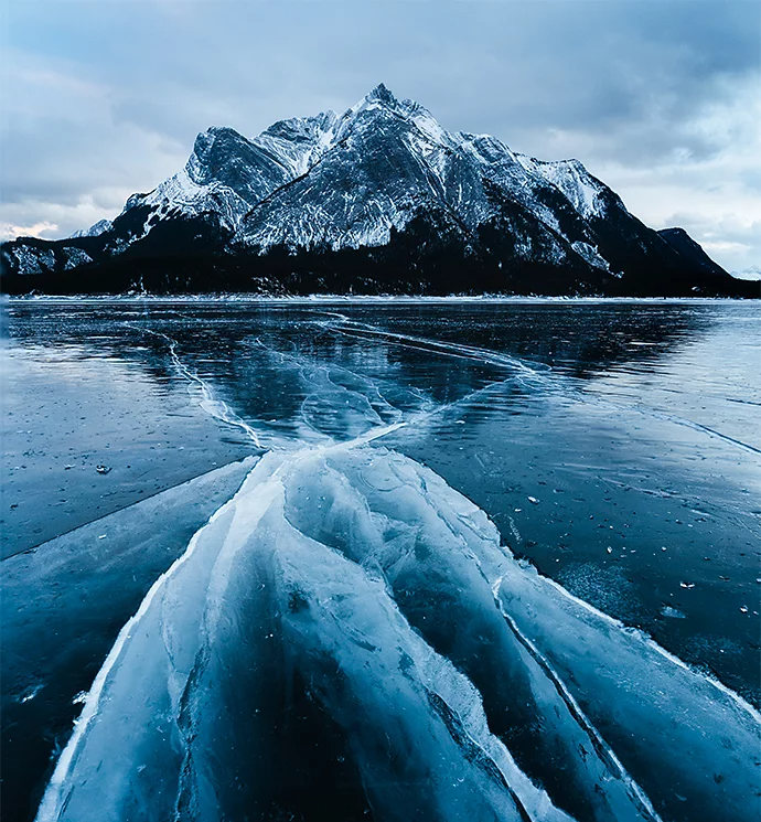 An icy lake with a snow-covered mountain in the background