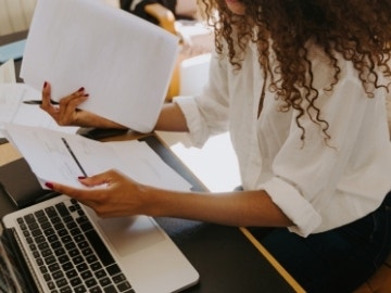 A woman sitting at a desk with her laptop while using home document management software.