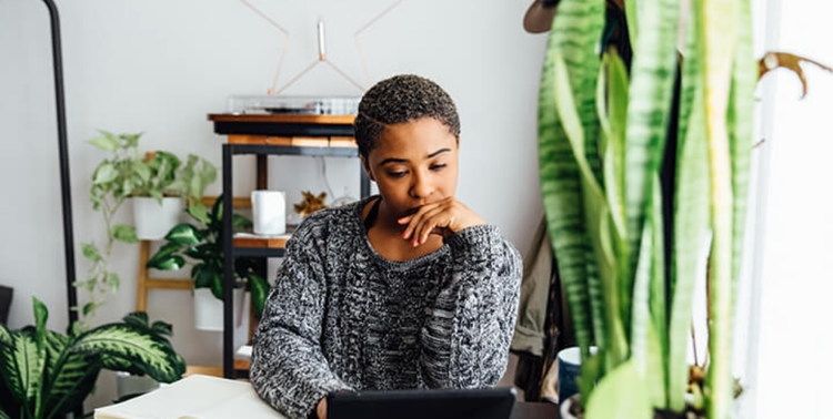 A person working remotely on a laptop at a desk in their home