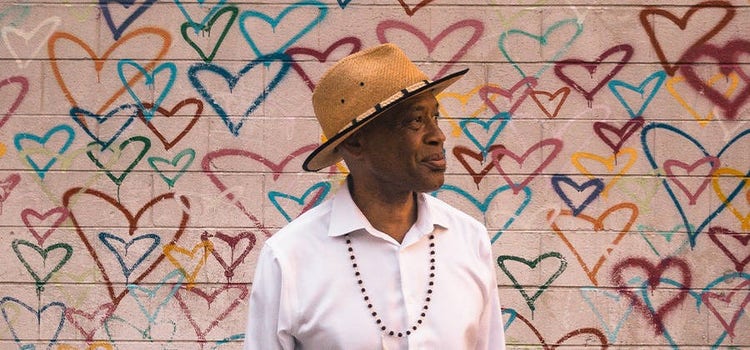 Inspirational headshot photo of a man in front of a wall of graffiti hearts.