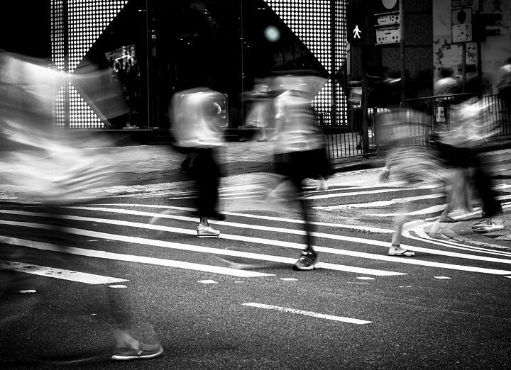 A motion blur time lapse photo of people walking on the street.