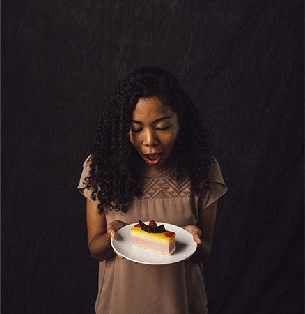 Headshot image of a woman amazed by the beautiful dessert she is holding.