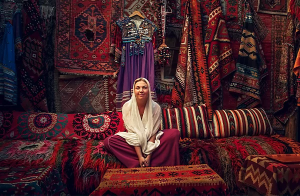 Person sitting in room full of carpets and red upholstery