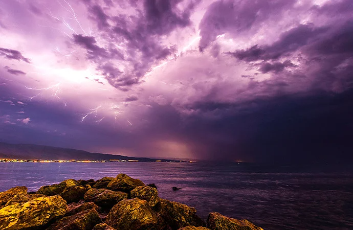 Photo of lightning streaks across the sky and illuminates the clouds