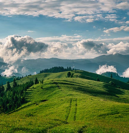 Beautiful nature shot of green hills stretching towards a cloud filled horizon.