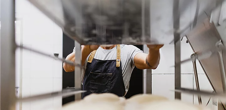 A viewpoint between two bakery trays as a baker puts a tray down