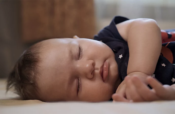 A photo of a baby sleeping on the floor with their face in focus