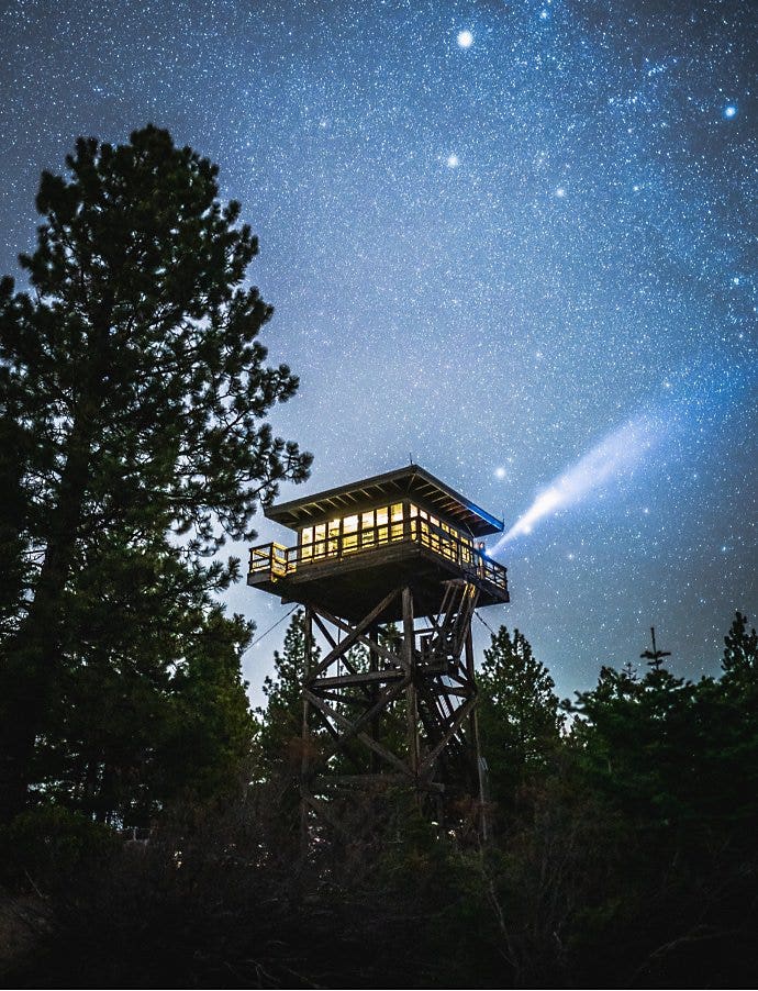 The Milky Way behind a ranger fire watch station in a forest