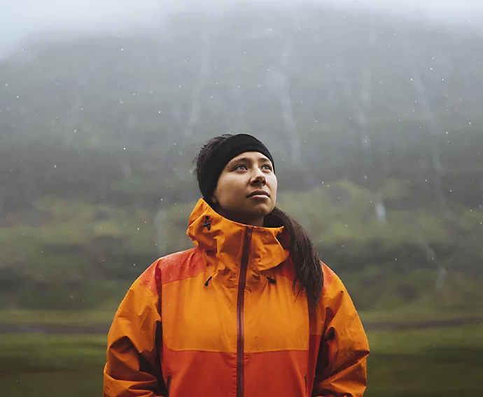 A person wearing an orange jacket standing out in the rain